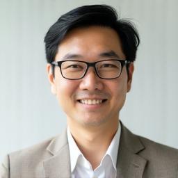 Professional headshot of Kenji Tanaka, a friendly looking man with short dark hair and glasses.